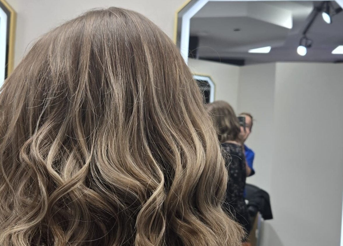 Coiffure bouclée chez Salon Suite 26, Longueuil, Québec, CA, reflet dans miroir lumineux.