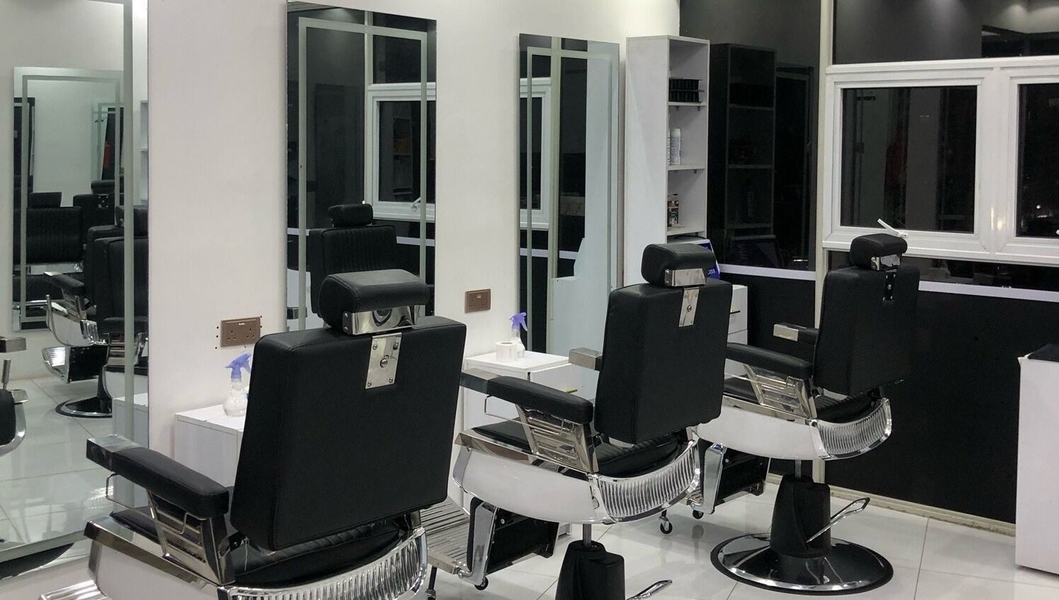 Modern interior of Artistic Grooming Parlour, Nairobi, Nairobi County, KE with sleek black barber chairs.
