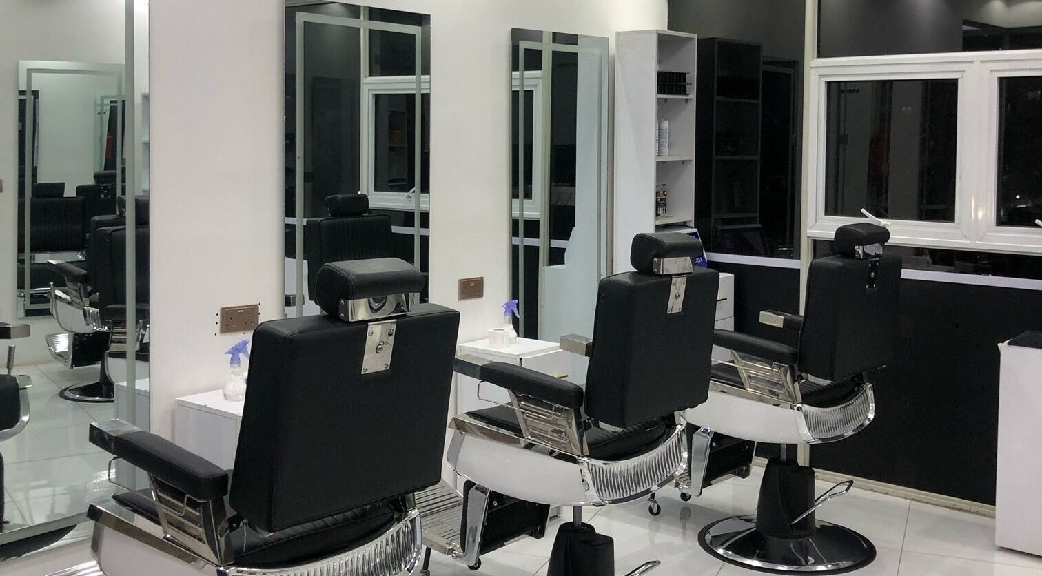 Modern interior of Artistic Grooming Parlour, Nairobi, Nairobi County, KE with sleek black barber chairs.