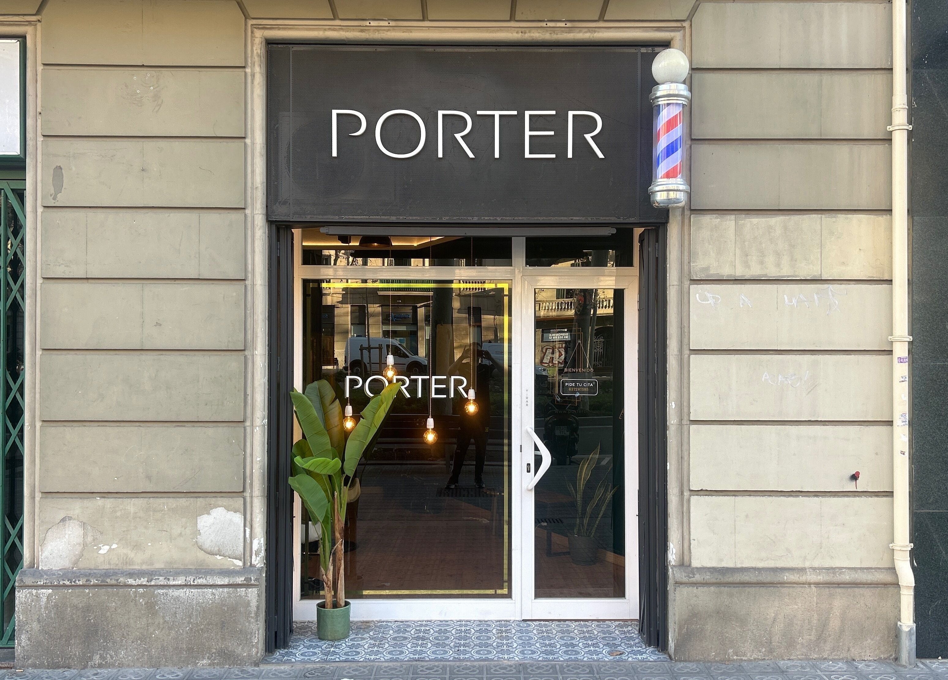 Entrance of Porter BCN Barbershop, Barcelona, Catalunya, ES, with elegant signage and green plants.