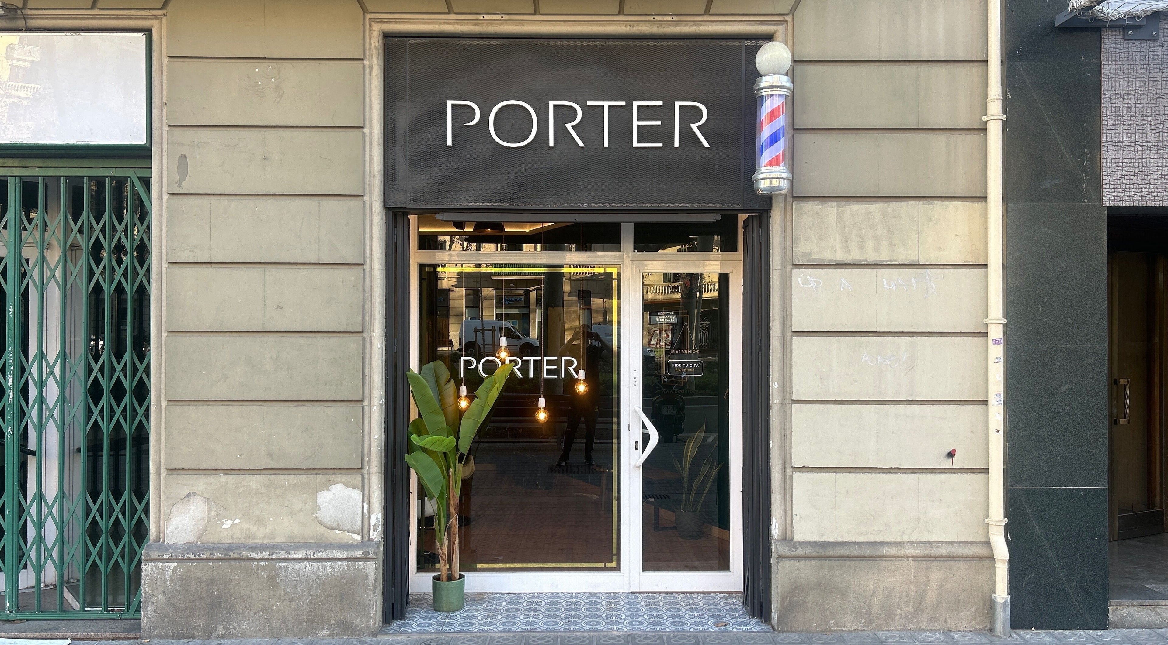 Entrance of Porter BCN Barbershop, Barcelona, Catalunya, ES, with elegant signage and green plants.