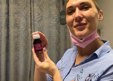 Smiling woman holding skincare product at Lavish Skincare, Somerset West, Western Cape, ZA.