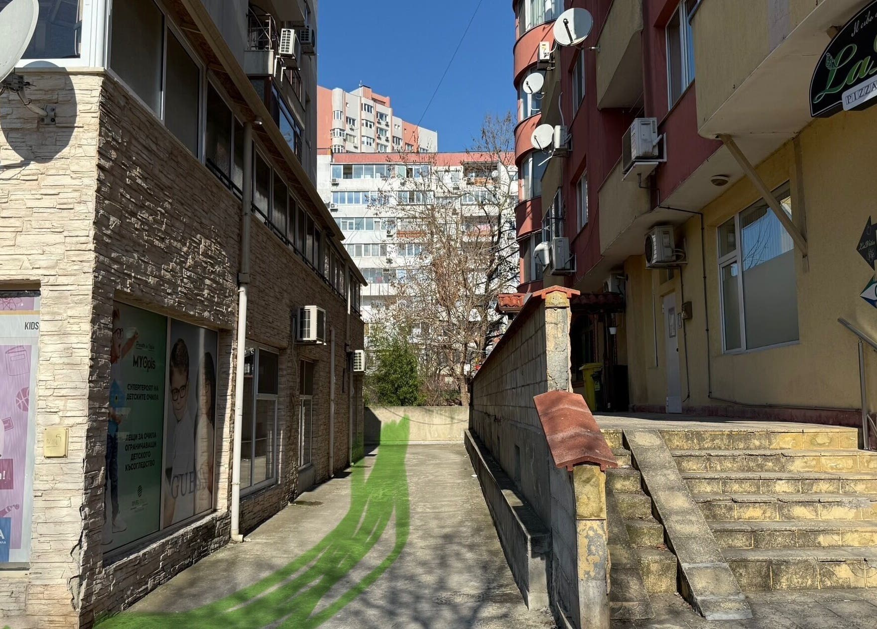 Уютна уличка води към Witchy Nails във Варна, Варна, BG, с модерни сгради наоколо.