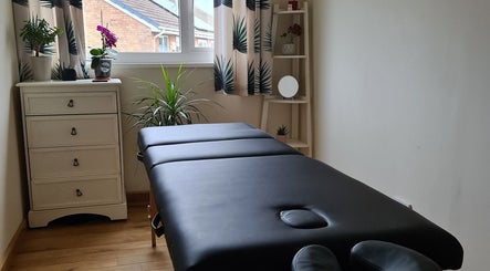 Massage table at Malvern Massage & Bodywork, Malvern, England, GB, in a calm room with plants and decor.