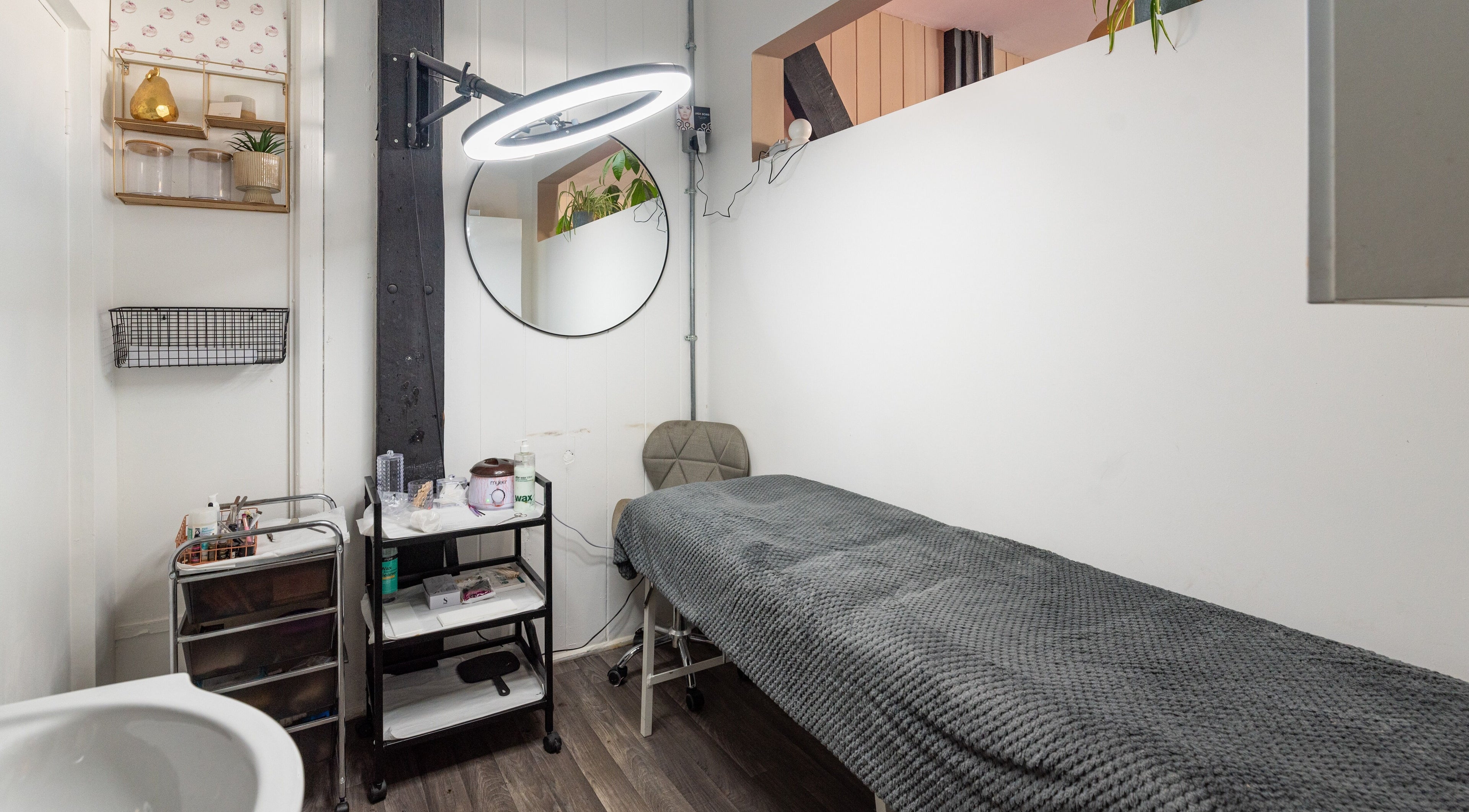 Relaxing treatment room at Sosta, Ash, England, GB with a cozy bed and sleek decor.