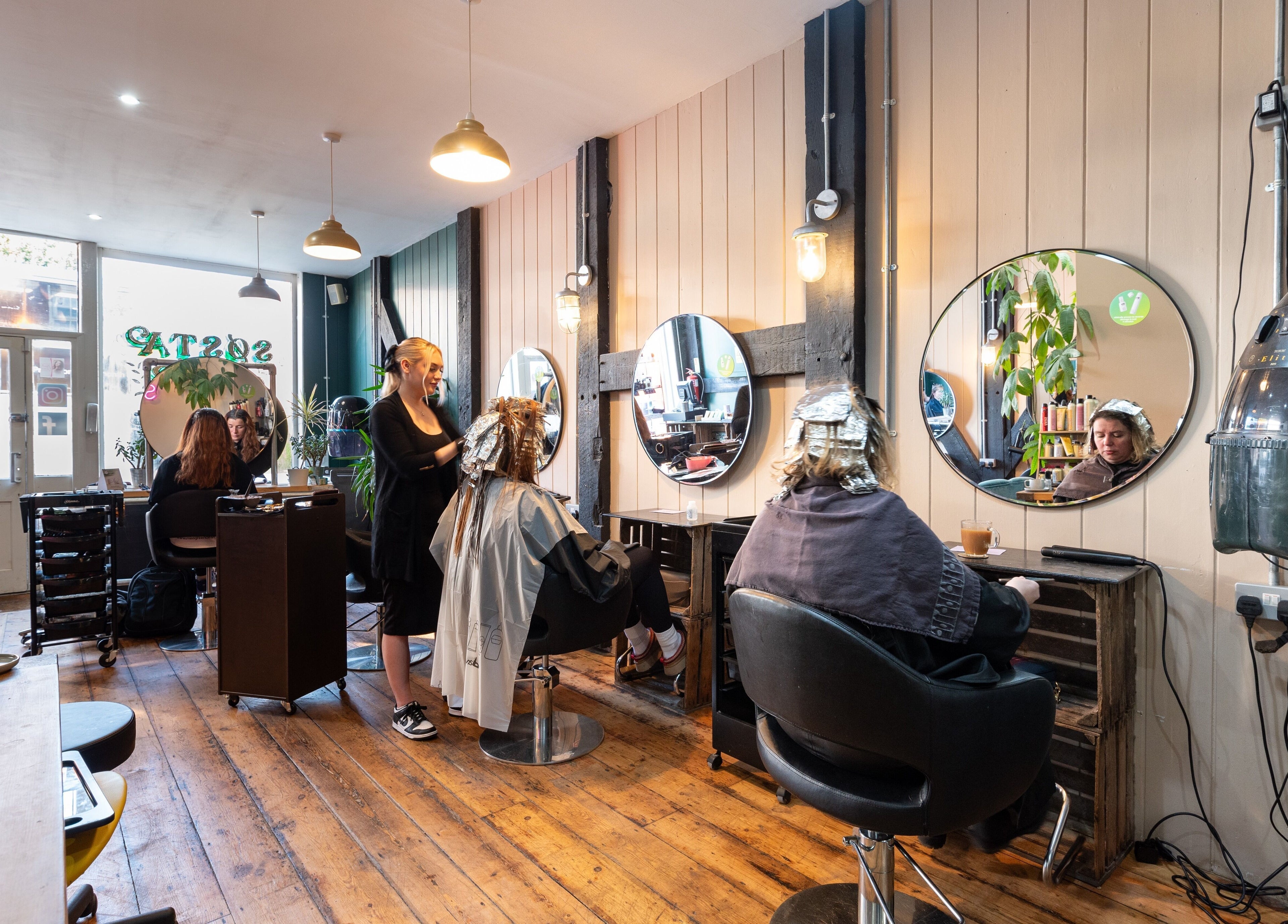 Stylish salon interior at Sosta, Ash, England, GB, showcasing customers in chic hair treatments.