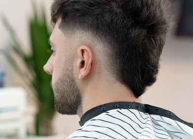 A man with a fresh haircut at ST8MNT Barbers in Gibraltar, GI, showcasing expert barbering skills.