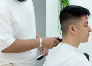 Barber styling hair at ST8MNT Barbers, Gibraltar, GI, showcasing modern grooming techniques.