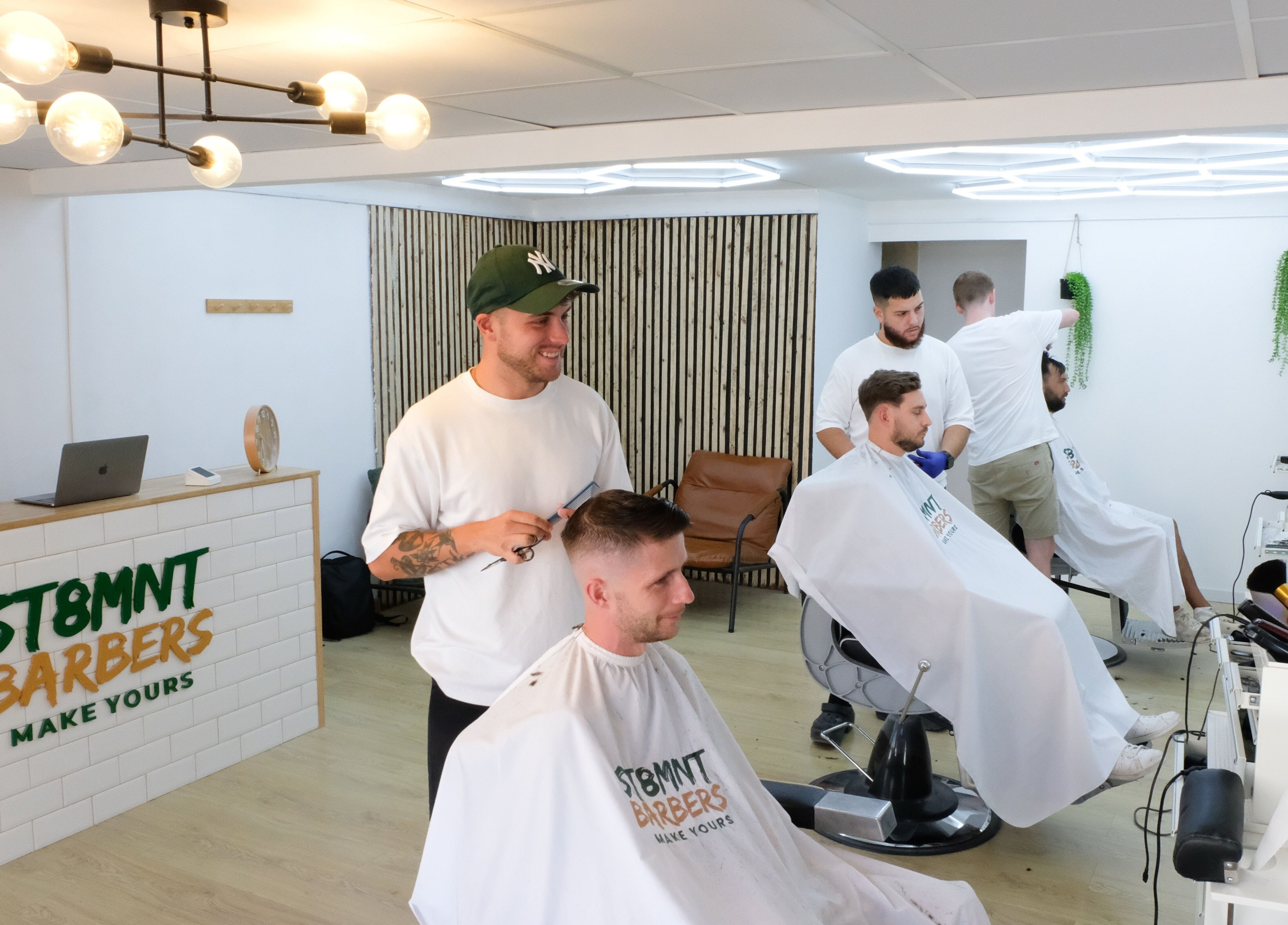 Inside ST8MNT Barbers in Gibraltar, GI. Barbers styling clients' hair in a modern, welcoming setting.