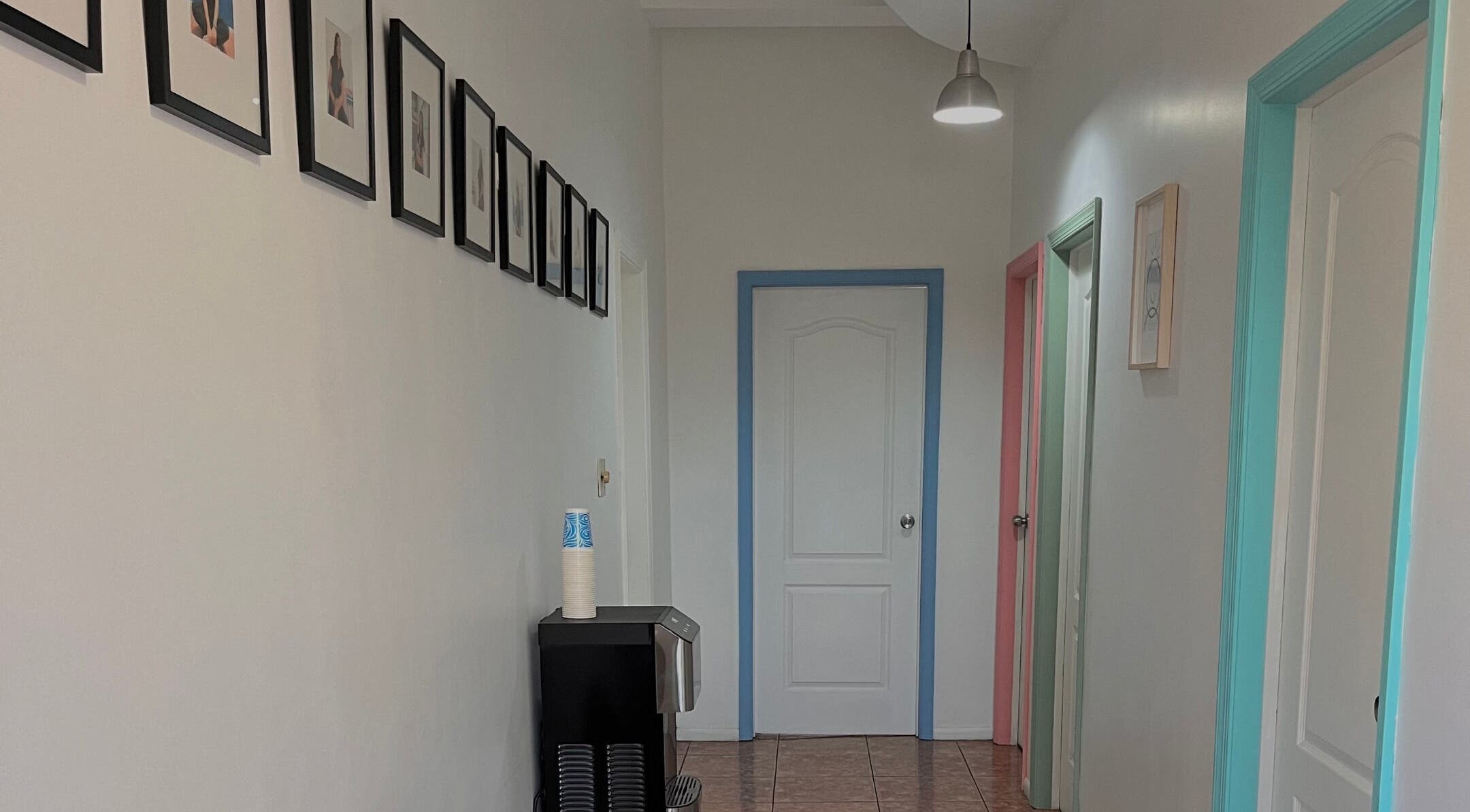 Pasillo colorido en Minds and Smiles, Playas De Rosarito, Baja California, MX, con fotos enmarcadas y puertas.