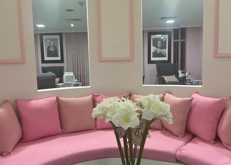 Elegant pink lounge area in Sugarcoat Nails, Abu Dhabi, AE, featuring plush cushions and floral decor.