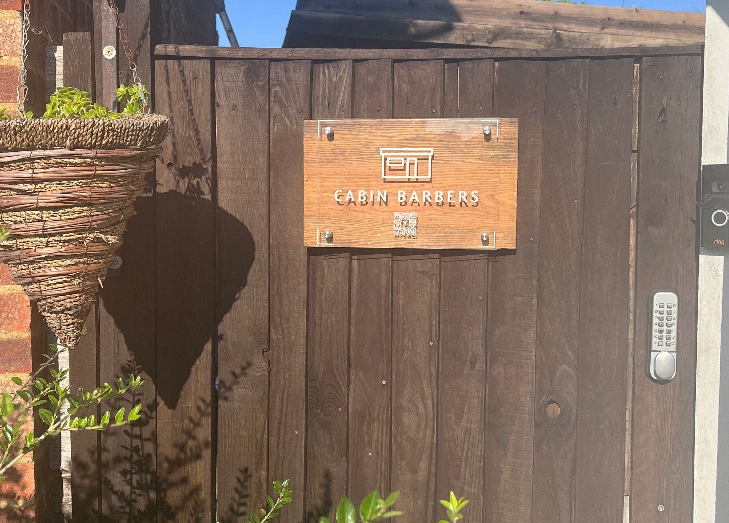 Wooden gate with Cabin Barbers sign in Chessington, England, GB.