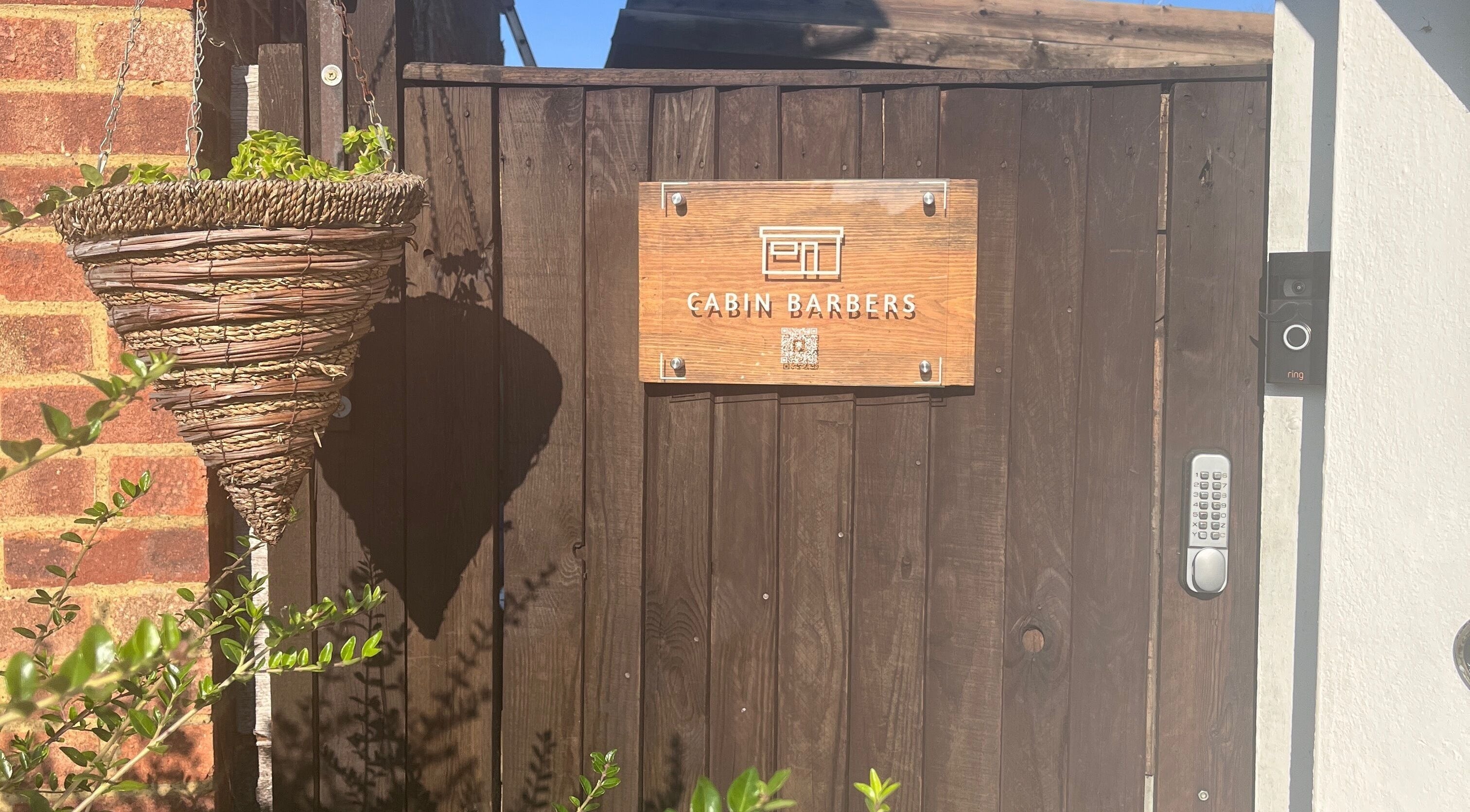 Wooden gate with Cabin Barbers sign in Chessington, England, GB.