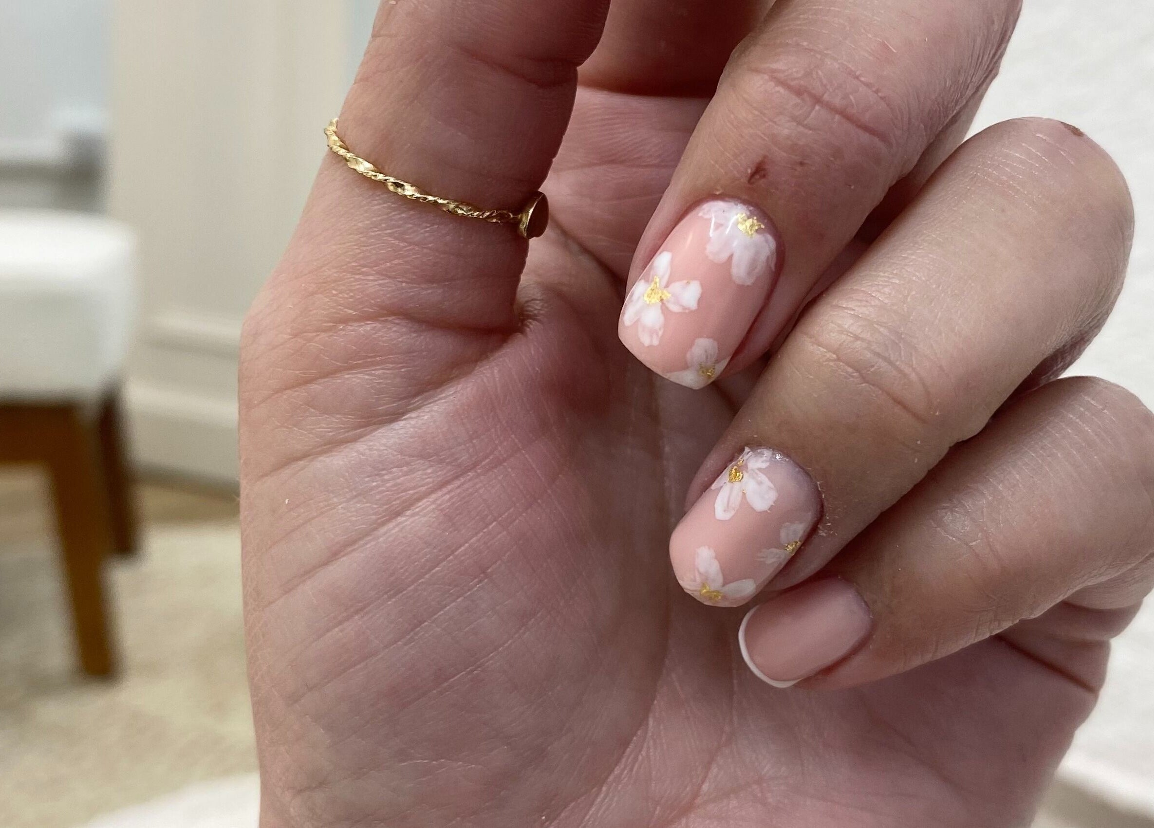 Floral nail art at Cure The Nail Studio, Oswestry, England, GB, showcasing delicate white flowers on peach nails.