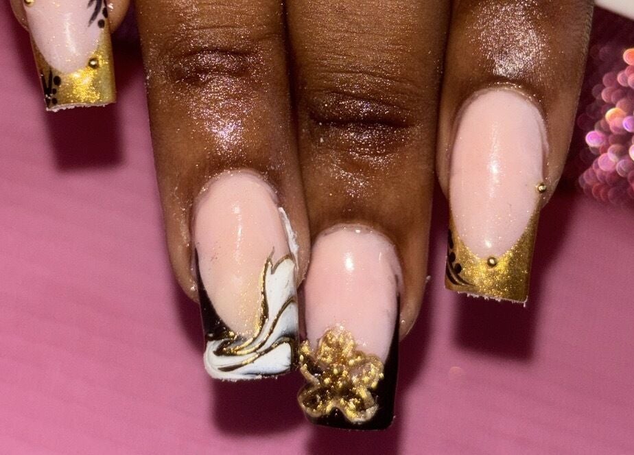 Elegant gold-accented nail art by SquaredByT in Cole Bay, Sint Maarten, SX, set against a pink backdrop.
