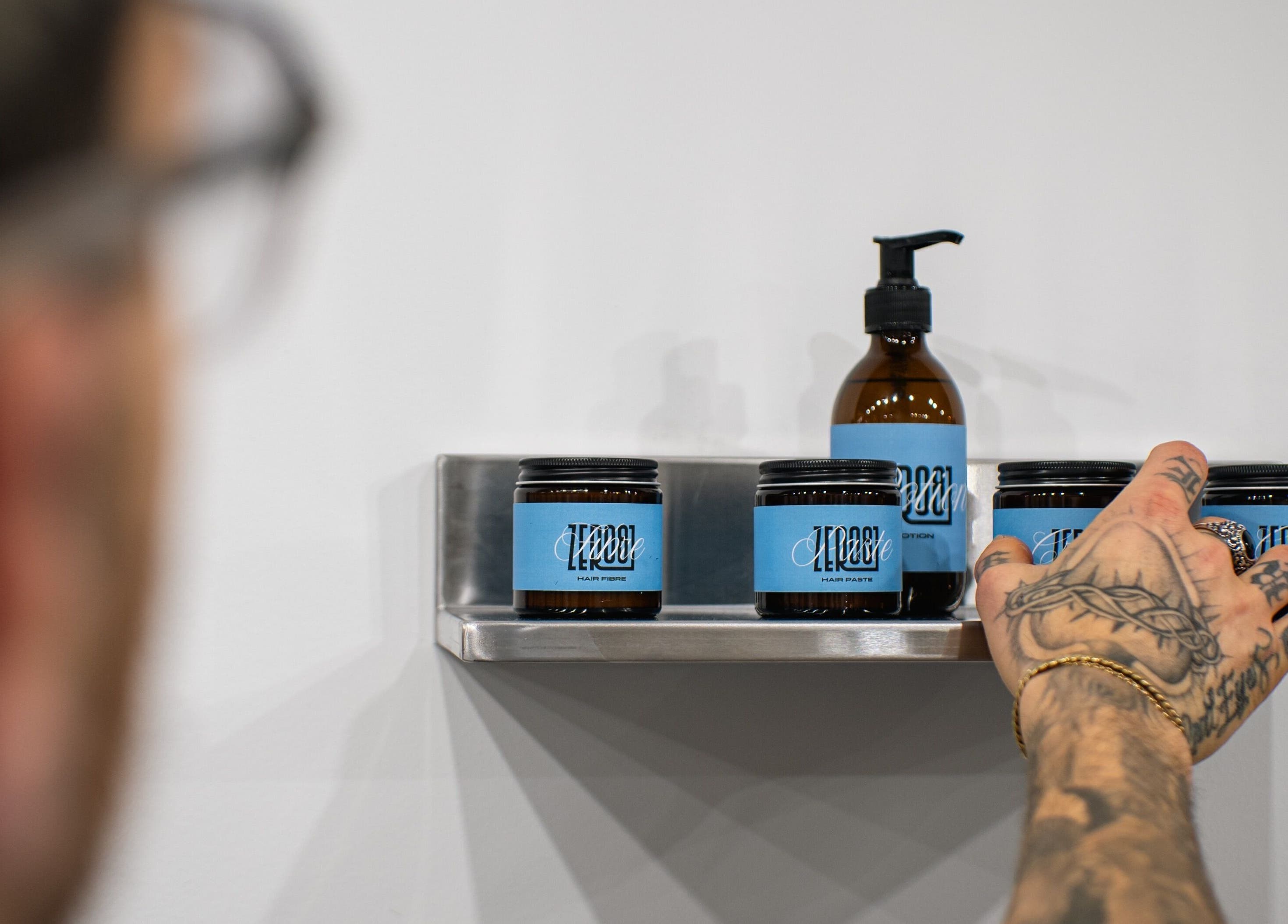A hand reaches for hair products on a shelf at ZERO81 Hair Studio - Caledonian Road, London, England, GB.