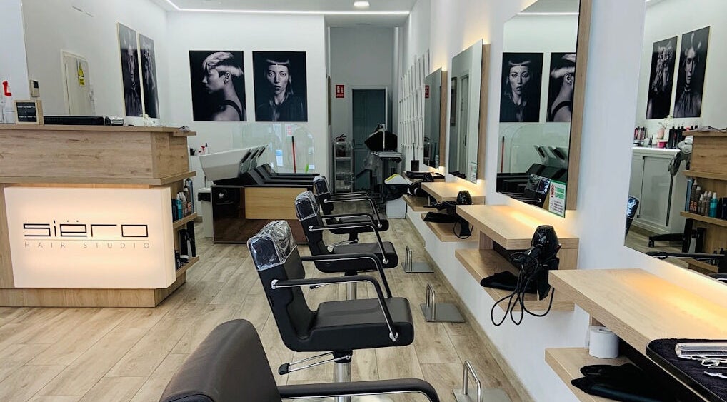 Interior de Siëro Hair en Madrid, Comunidad De Madrid, ES. Muestra sillones modernos y espejos iluminados.