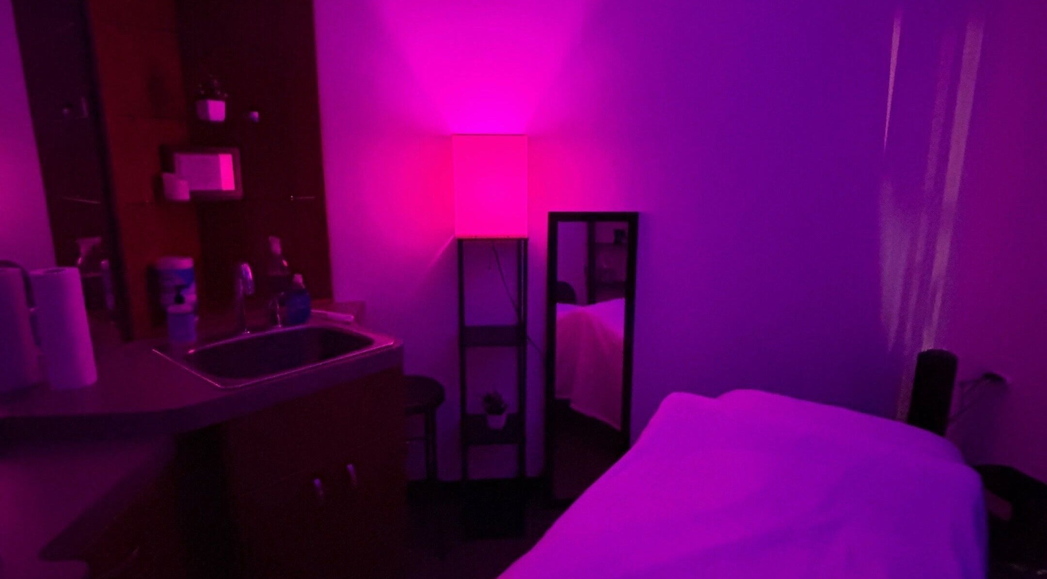 Soothing massage room at Moore Magic Massage, North Little Rock, Arkansas, US, with ambient purple lighting.