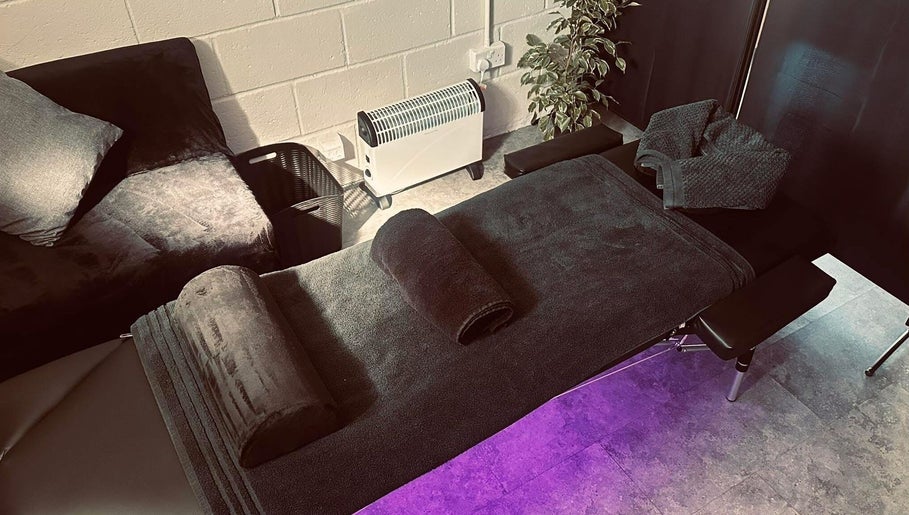 Peaceful massage setup at A.J.Healing, South Ockendon, England, GB with sleek black decor and ambient lighting.