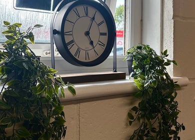 Elegant clock on a window sill adds charm to A.J.Healing in South Ockendon, England, GB, surrounded by lush greenery.