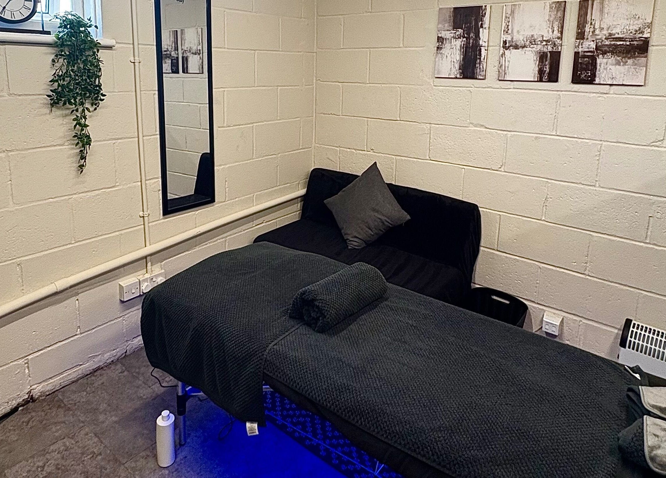 Serene massage room at A.J.Healing in South Ockendon, England, GB with a bed, cozy couch, and calming decor.