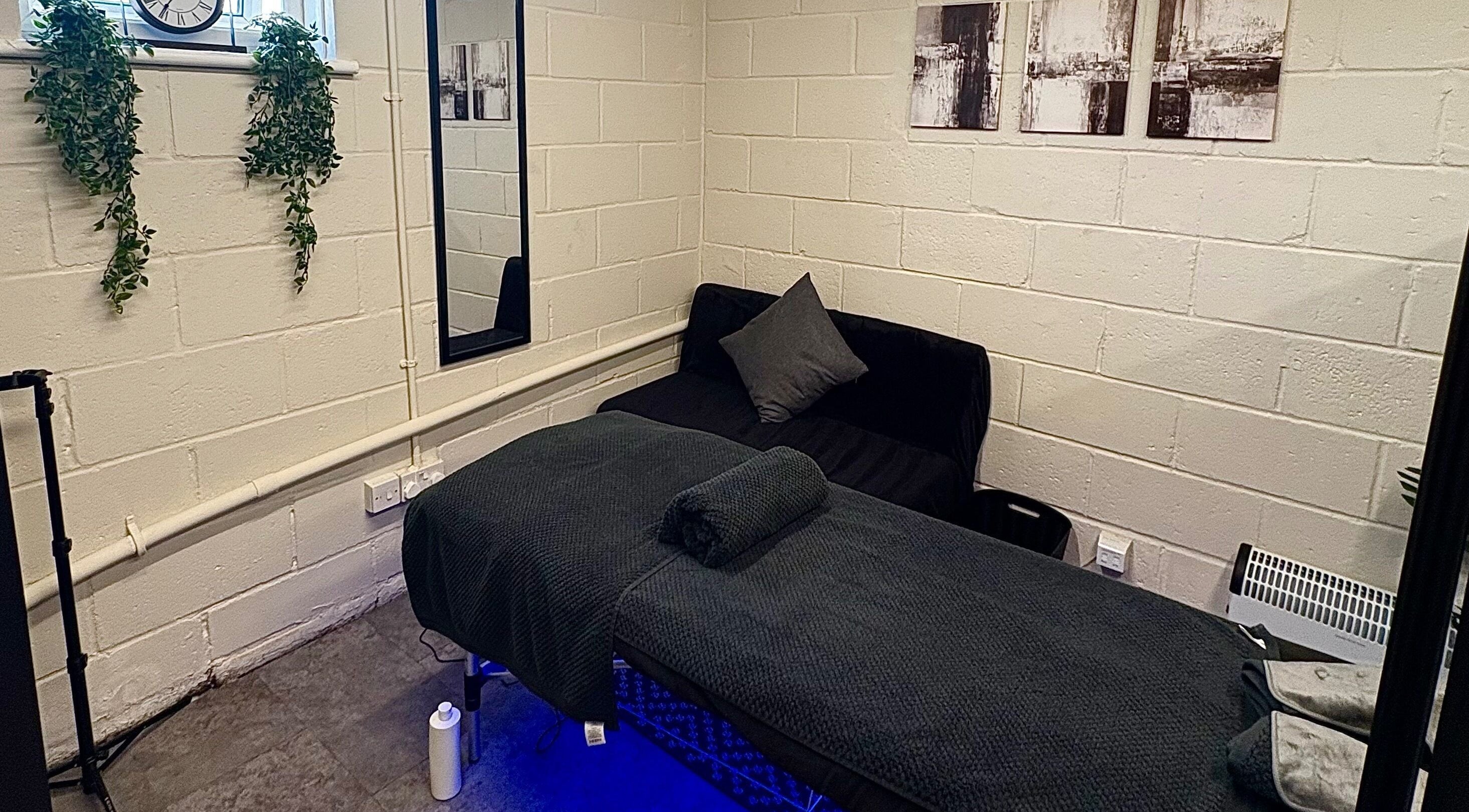 Serene massage room at A.J.Healing in South Ockendon, England, GB with a bed, cozy couch, and calming decor.