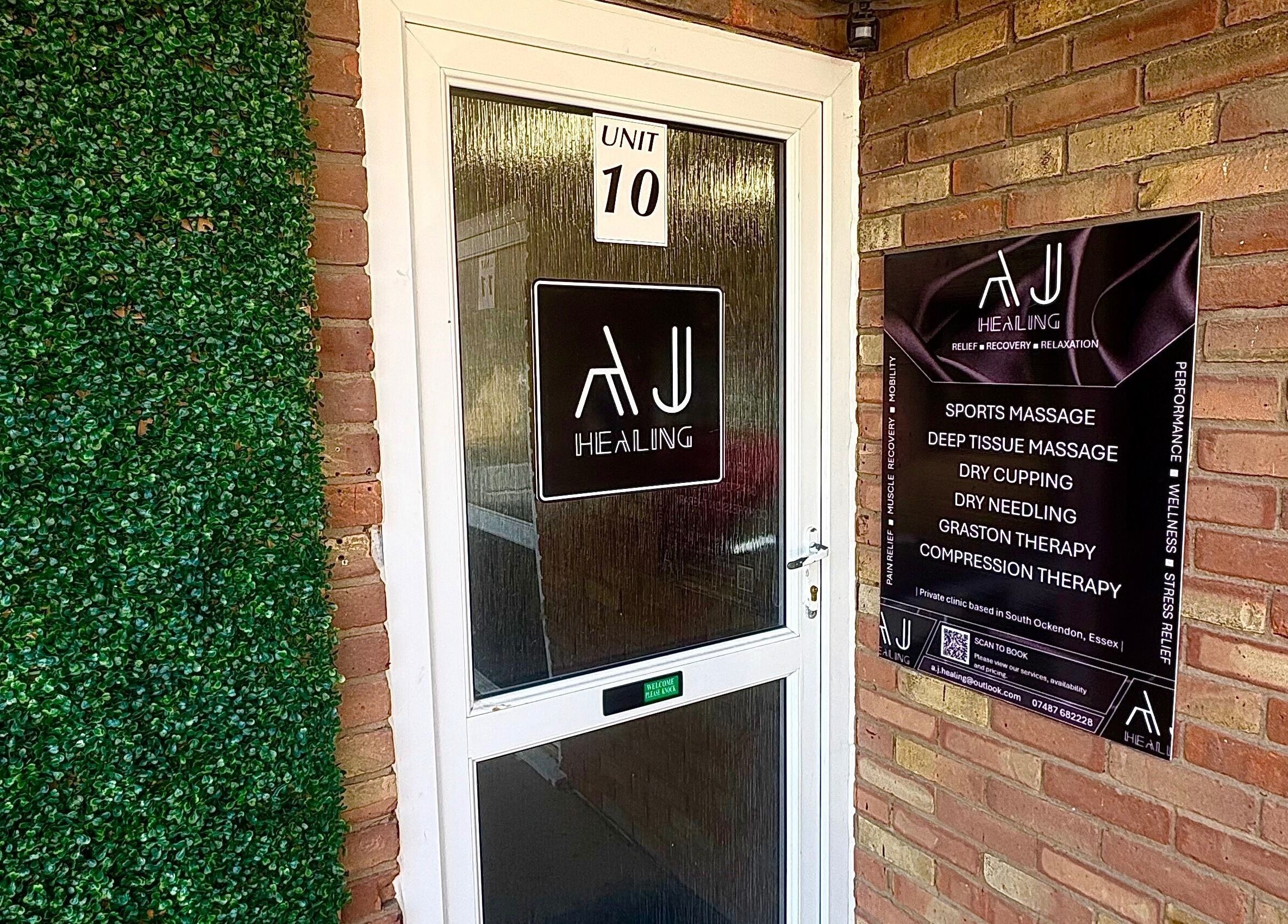 Entrance of A.J.Healing in South Ockendon, England, GB, showcasing a glass door and service board.