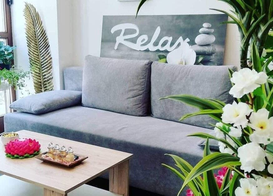 Entspannende Lounge bei Hi Spa 1, Wien, Wien, AT, mit grauem Sofa, Pflanzen und Tee-Set auf Holztisch.