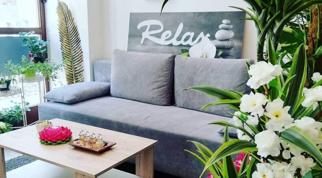 Entspannende Lounge bei Hi Spa 1, Wien, Wien, AT, mit grauem Sofa, Pflanzen und Tee-Set auf Holztisch.