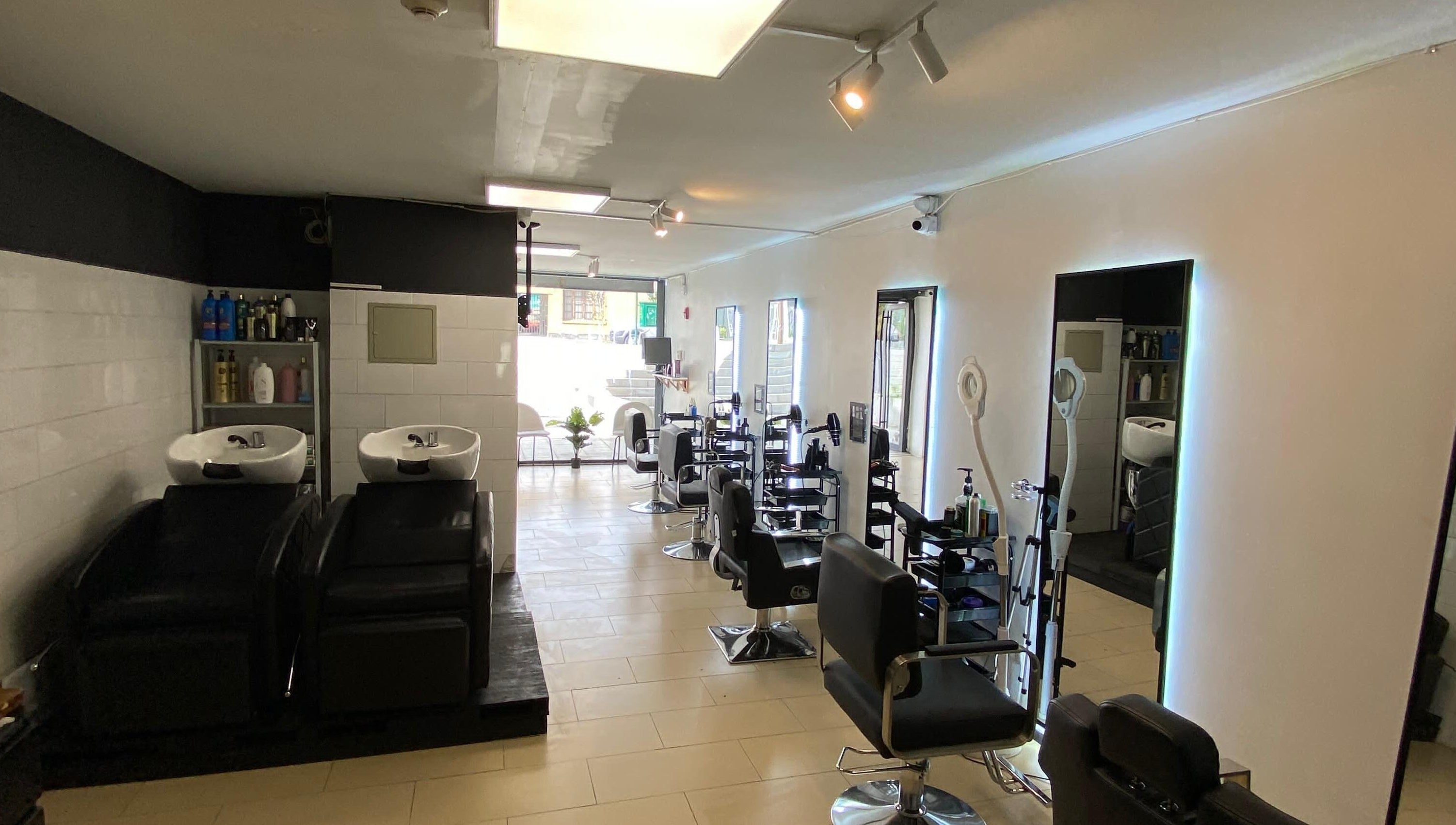 Interior moderno de Shaddai Salón de belleza y Barbería en Ñuñoa, Región Metropolitana, CL con sillas y espejos elegantes.