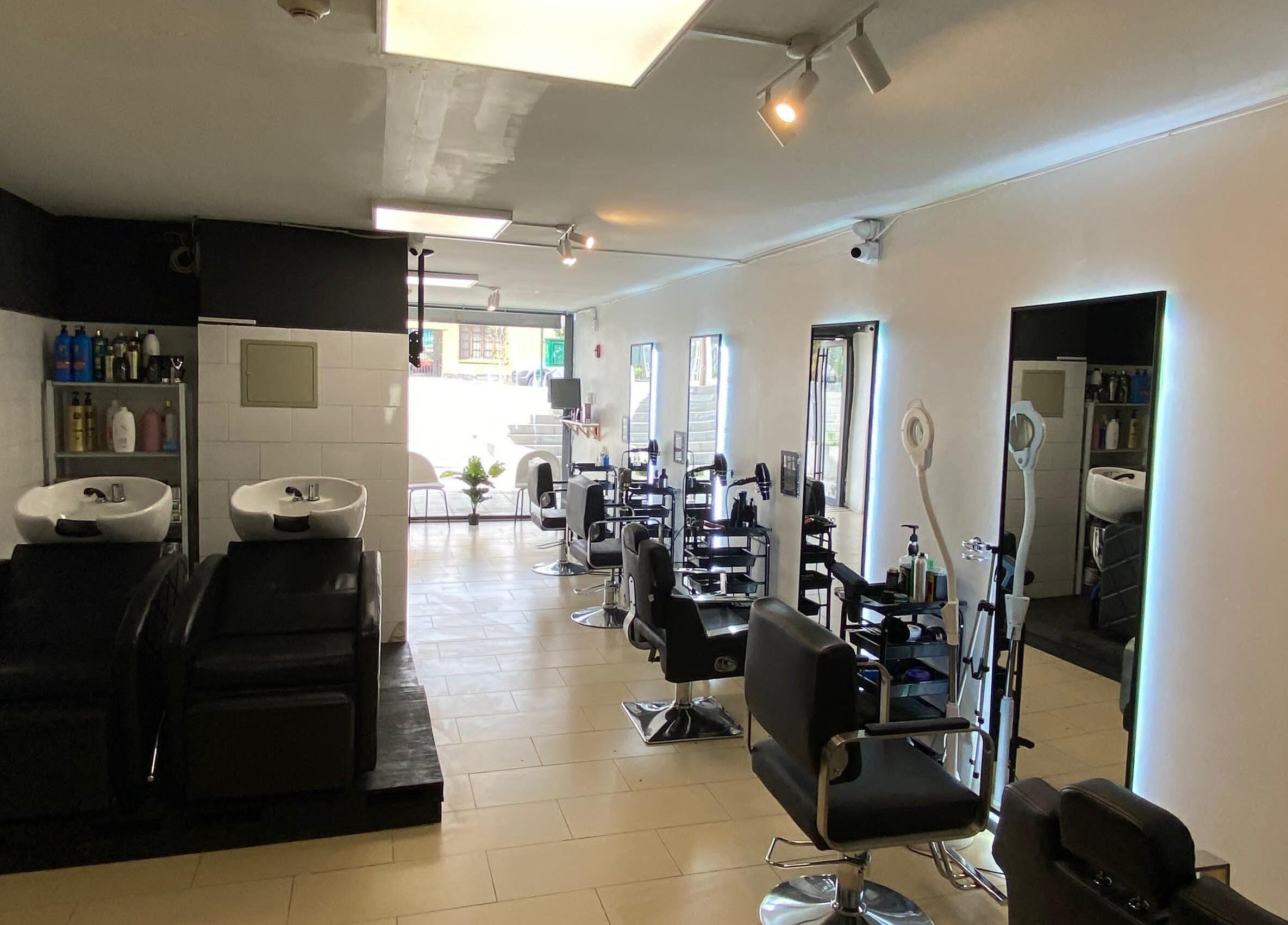 Interior moderno de Shaddai Salón de belleza y Barbería en Ñuñoa, Región Metropolitana, CL con sillas y espejos elegantes.