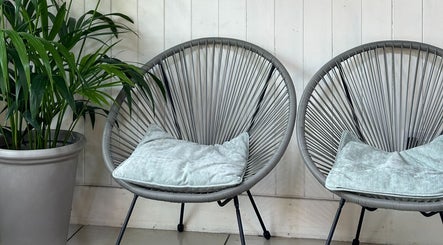 Stylish seating area at Siin Hair Beauty, Nottingham, England, GB with modern chairs and a lush plant.