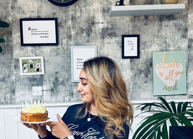 Woman with cake at Siin Hair Beauty, Nottingham, England, GB, surrounded by stylish decor.