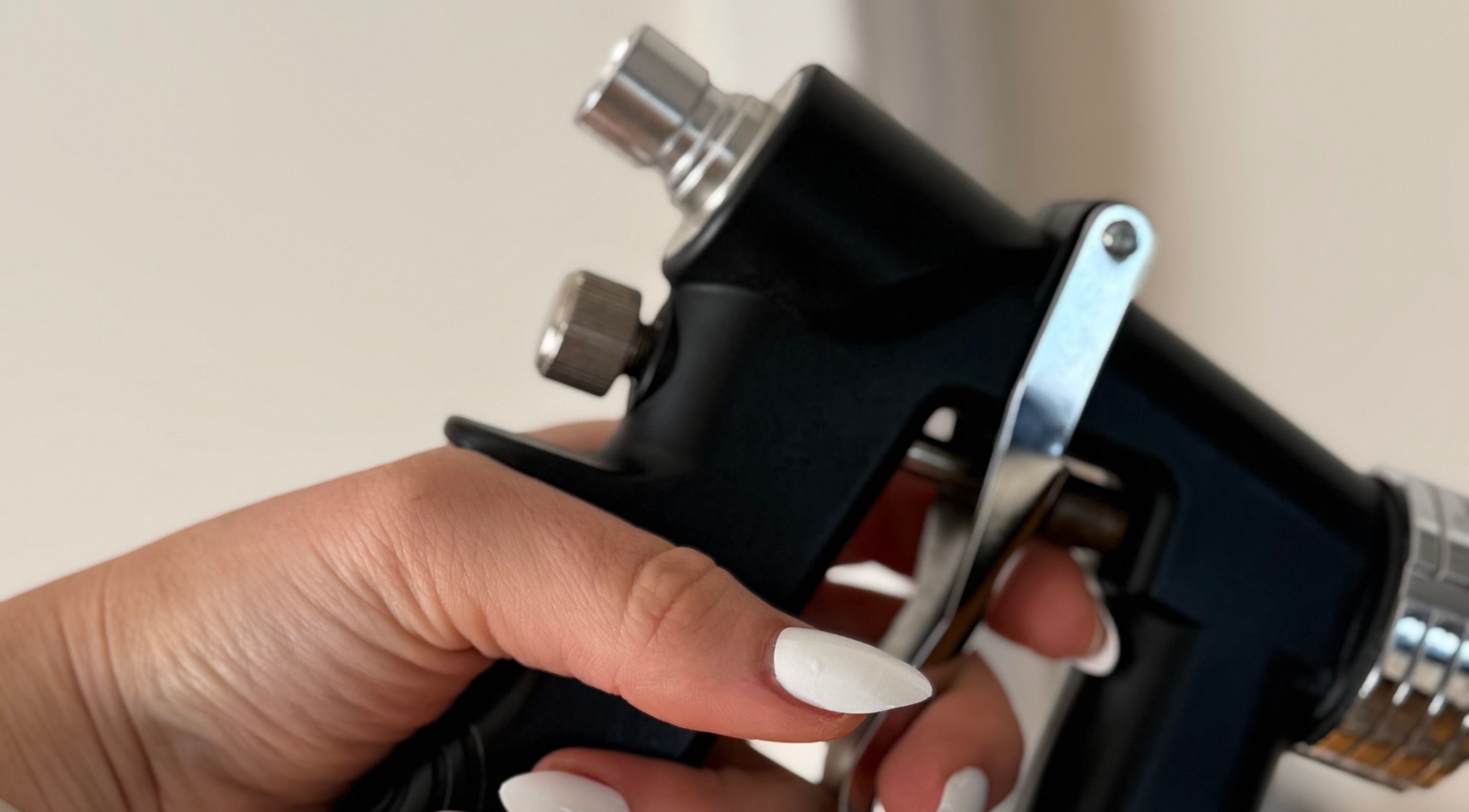 Close-up of hand with white nails holding a beauty tool at Magnetic Glow, Redcliffe, Queensland, AU.