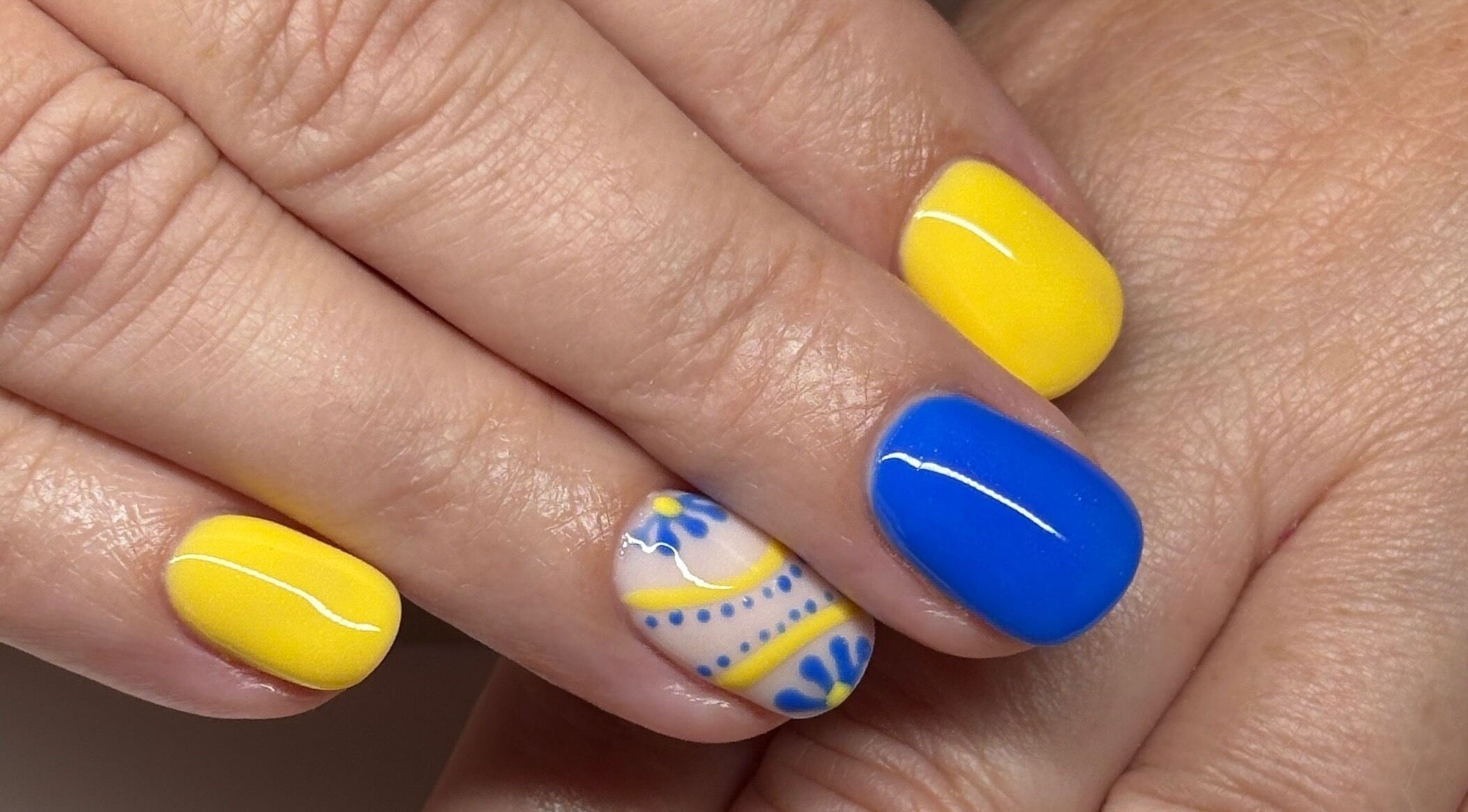 Vibrant blue and yellow nail art at Polished by Kate, Constantine, England, GB, showcasing intricate designs.