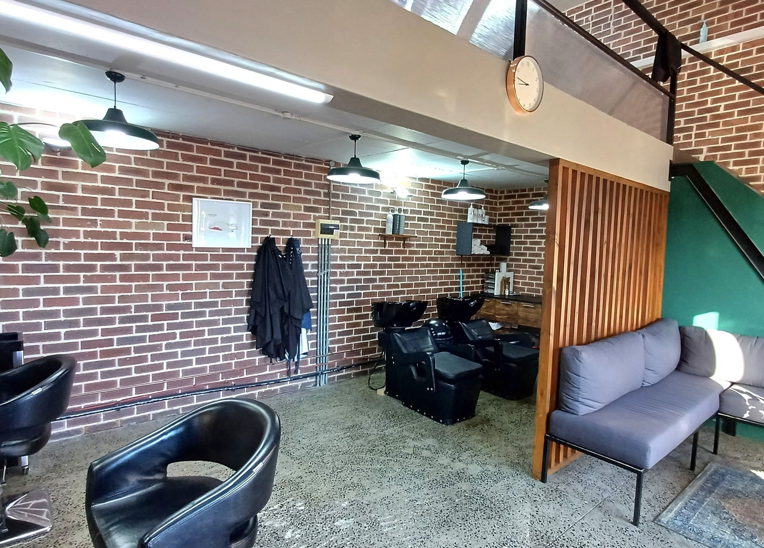 Modern interior of The Hadfield Hair, Cape Town, featuring a stylish brick wall and cozy seating area.