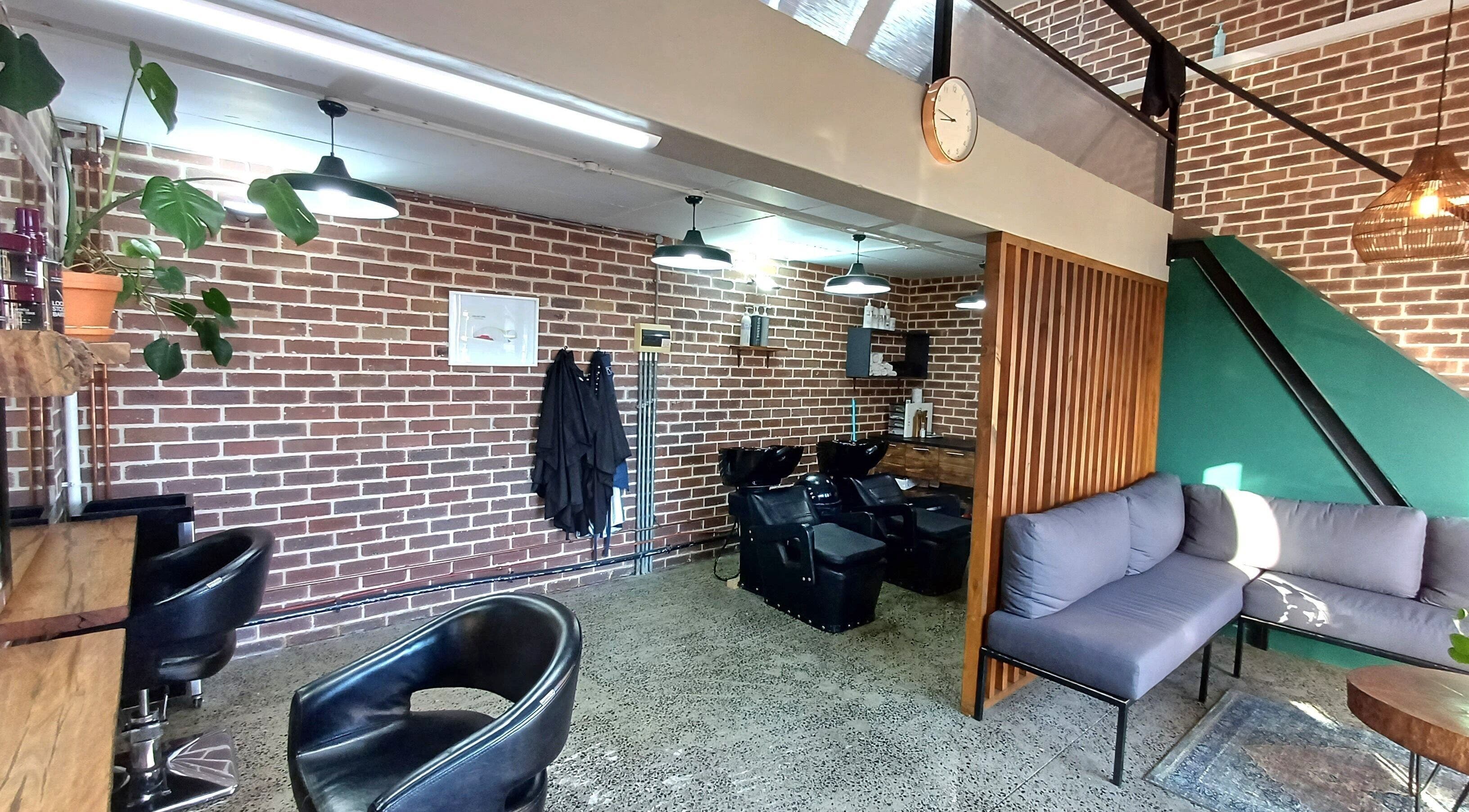 Modern interior of The Hadfield Hair, Cape Town, featuring a stylish brick wall and cozy seating area.