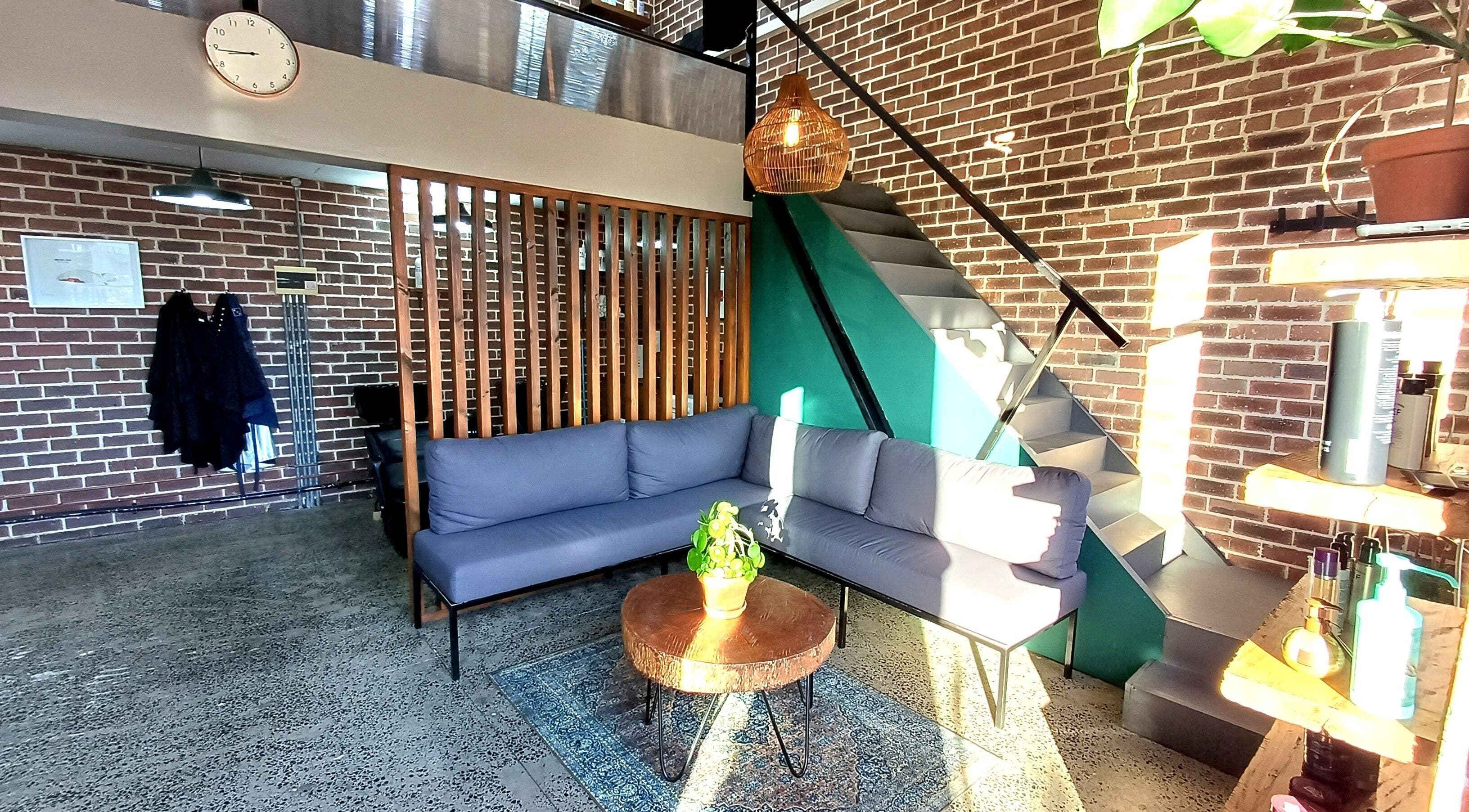 Modern lounge area at The Hadfield Hair, Cape Town, Western Cape, ZA featuring cozy seating and rustic decor.