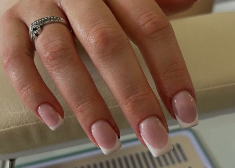 Elegant French manicure at The Collective, Edinburgh, Scotland, GB. A polished hand on a plush cushion.