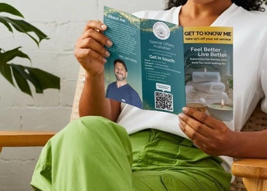 Person reading a Wellbeing Massage & Pain Relief in Covent Garden brochure, London, England, GB.