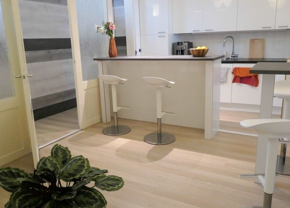 Moderne keukenhoek Be Silk Leiden met witte meubels, barstoelen in Leiden, Zuid-Holland, NL.