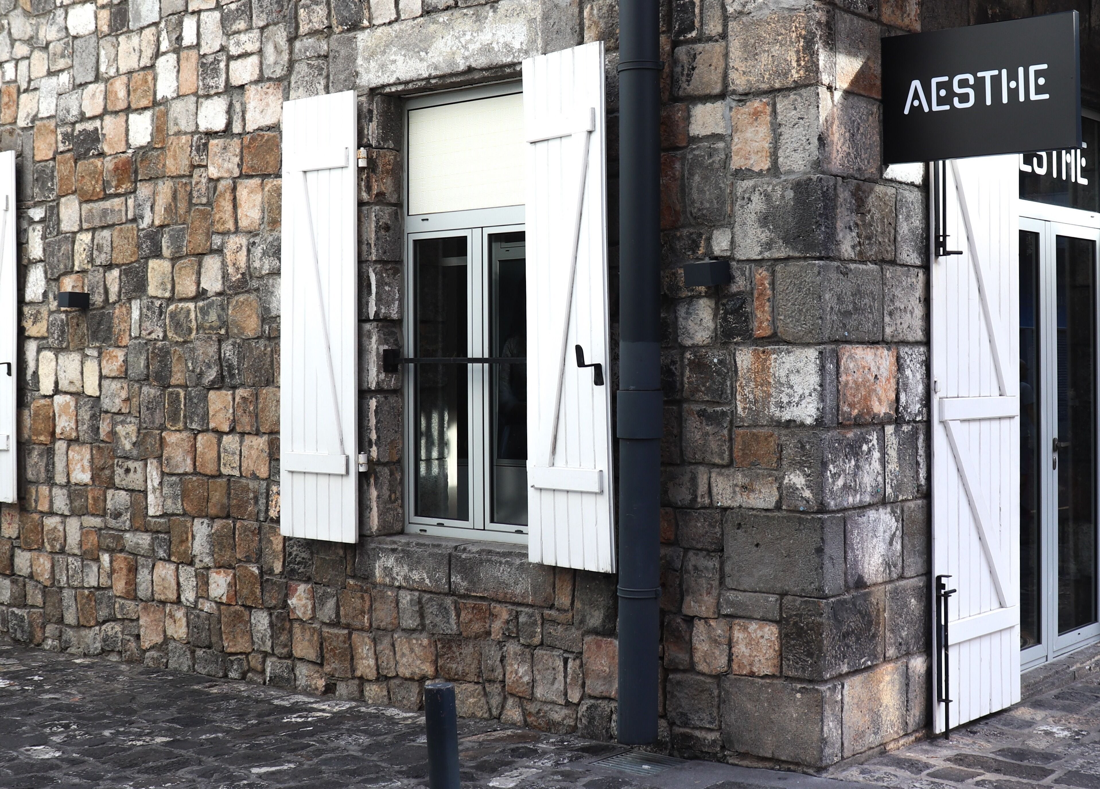 Entrance of Aesthe, Port Louis, Port Louis District, MU, showcasing rustic stone wall and stylish windows.
