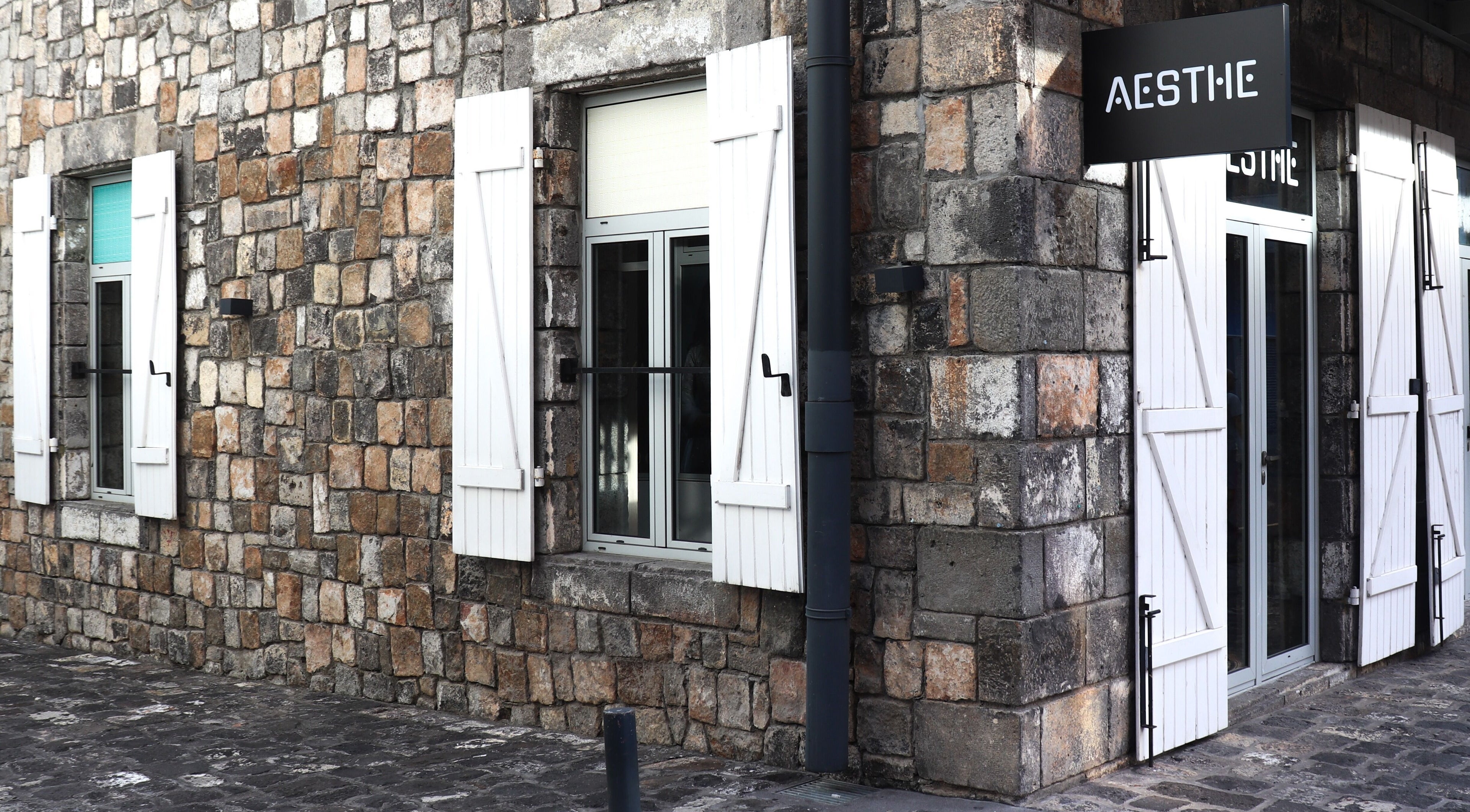 Entrance of Aesthe, Port Louis, Port Louis District, MU, showcasing rustic stone wall and stylish windows.