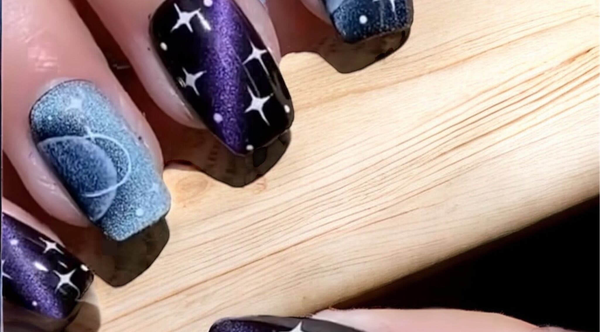 Kiwiinails Pro in Fenton, Michigan offers stunning galactic-themed nail art with starry night designs.