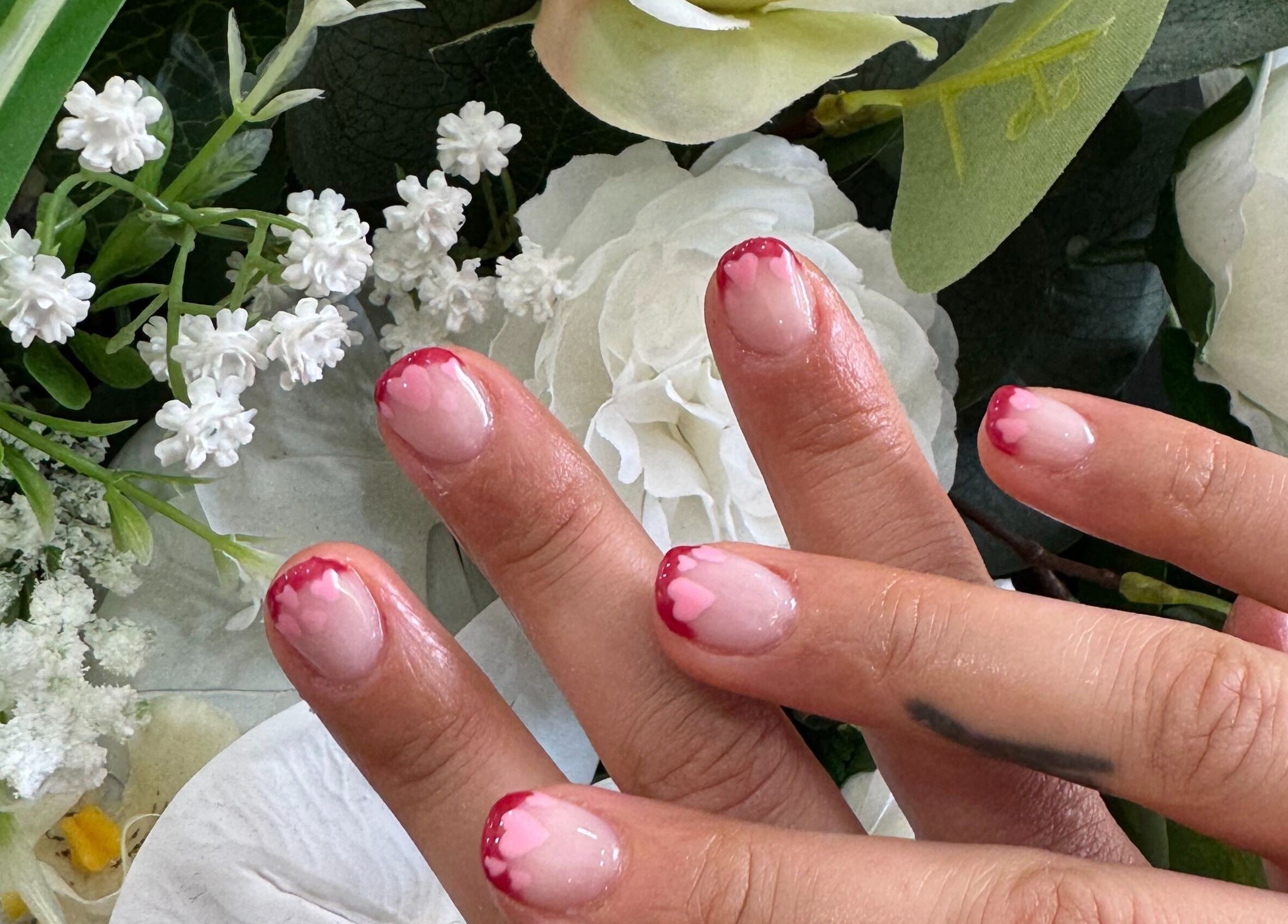 Elegant pink heart nail art with floral backdrop at Magnolia Beauty Bar, Mildura, Victoria, AU.