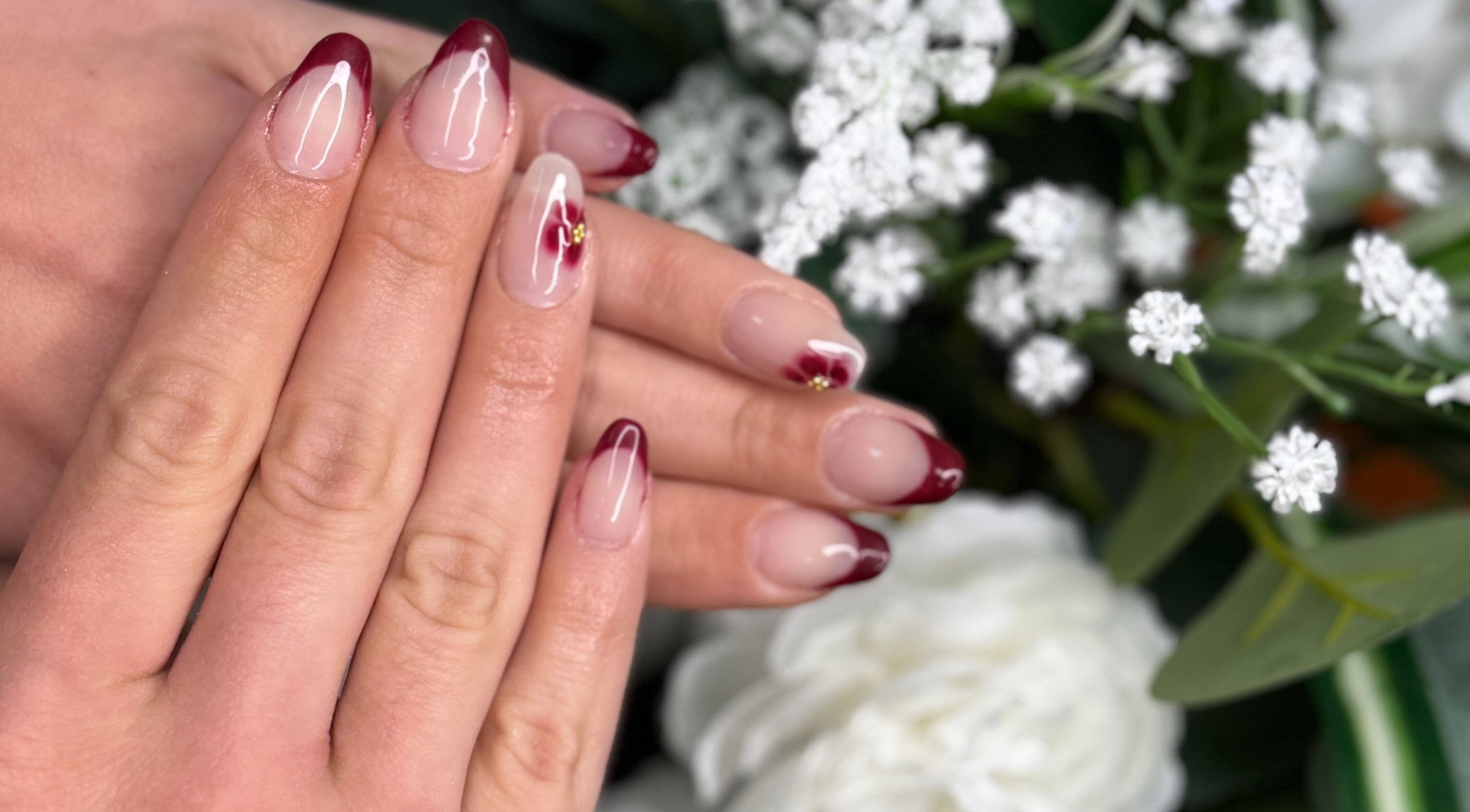 Dainty red-tipped nails at Magnolia Beauty Bar, Mildura, Victoria, AU surrounded by white flowers.