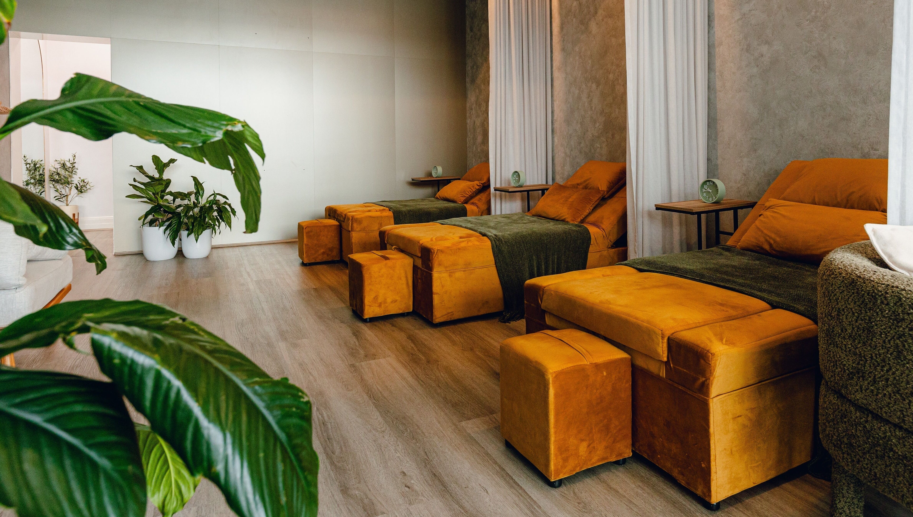 Relaxing lounge area at Newleaf Spa in Melbourne, Victoria, AU, featuring comfortable mustard seating and green plants.