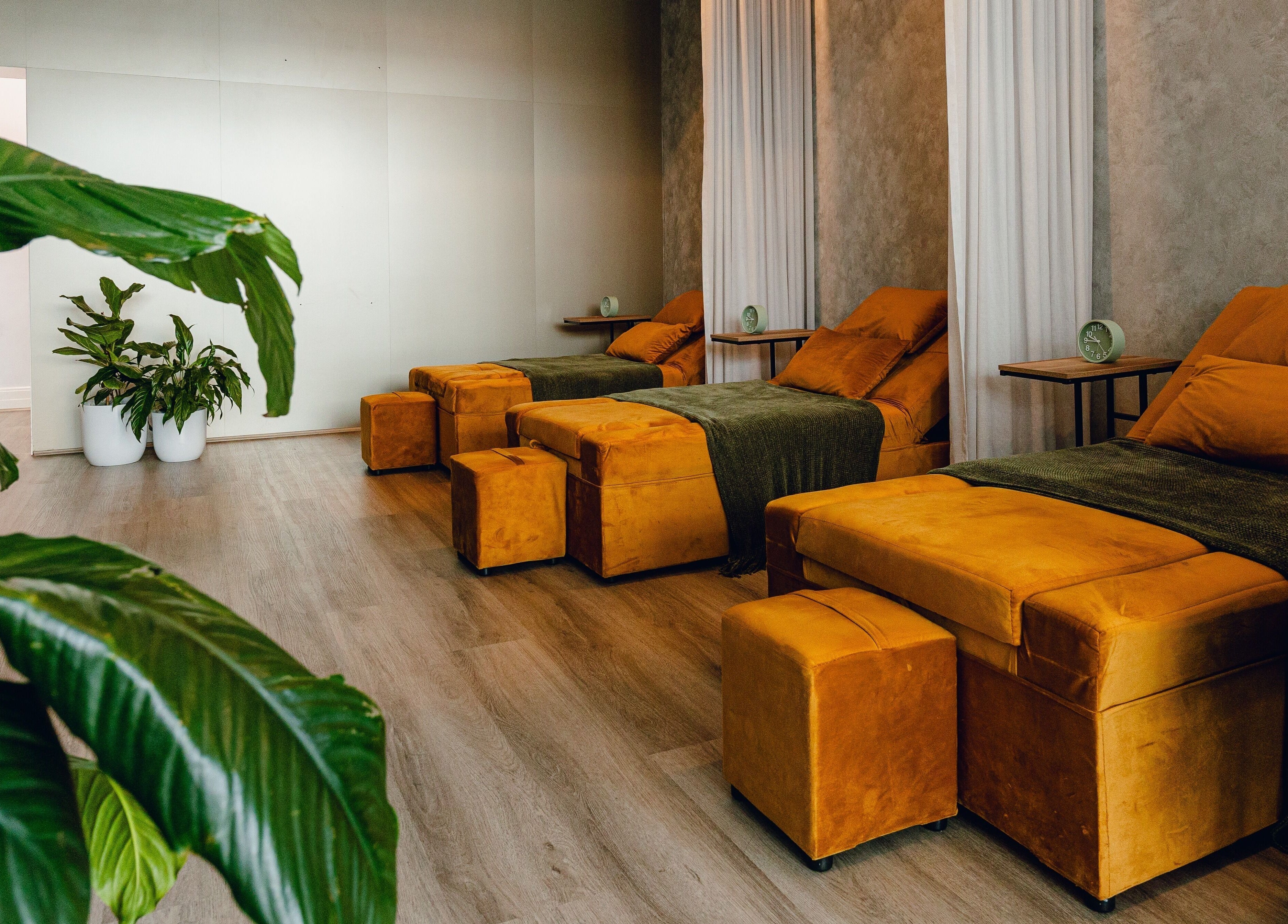 Relaxing lounge area at Newleaf Spa in Melbourne, Victoria, AU, featuring comfortable mustard seating and green plants.