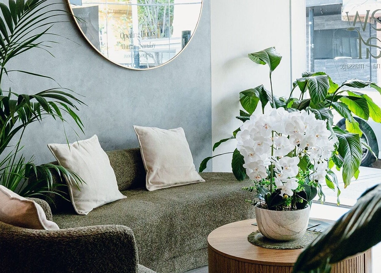 Relaxing lounge area at Newleaf Spa, Melbourne, Victoria, AU with green plants and cozy seating.