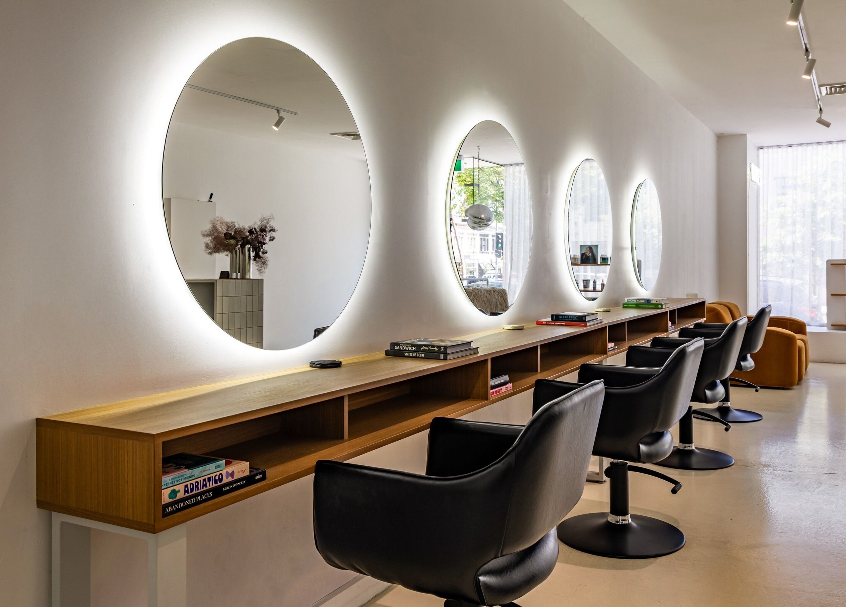 Elegant salon interior at WAVES in Melbourne, Victoria, AU highlighting modern chairs and glowing mirrors.
